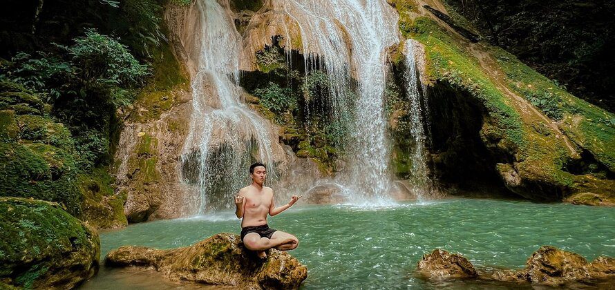 man meditating on a rock