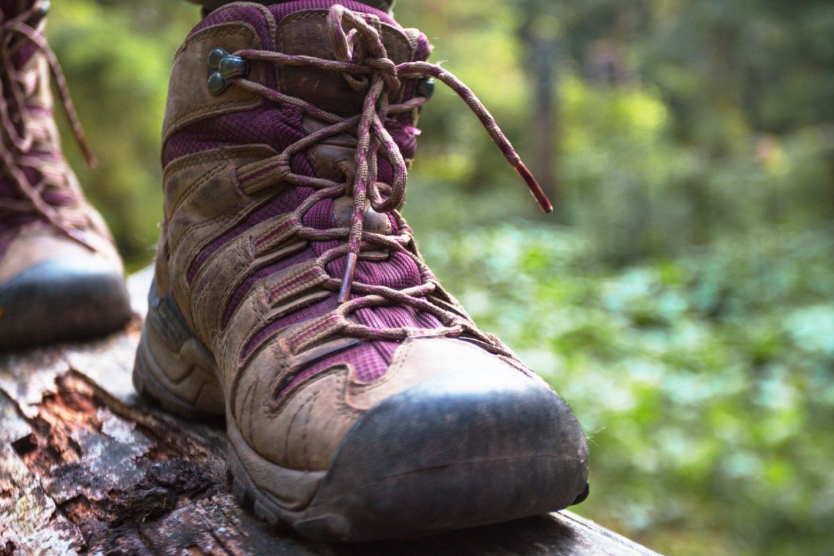 Do You Need Ankle Support for Hiking? (What You Must Know) Close-up of a hiker wearing supportive hiking boots on uneven terrain to improve ankle stability.