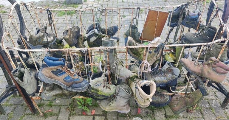 The Ultimate Outdoor Footwear Guide (All Types Explained & More) A bunch of worn out hiking boots hanging on a rack