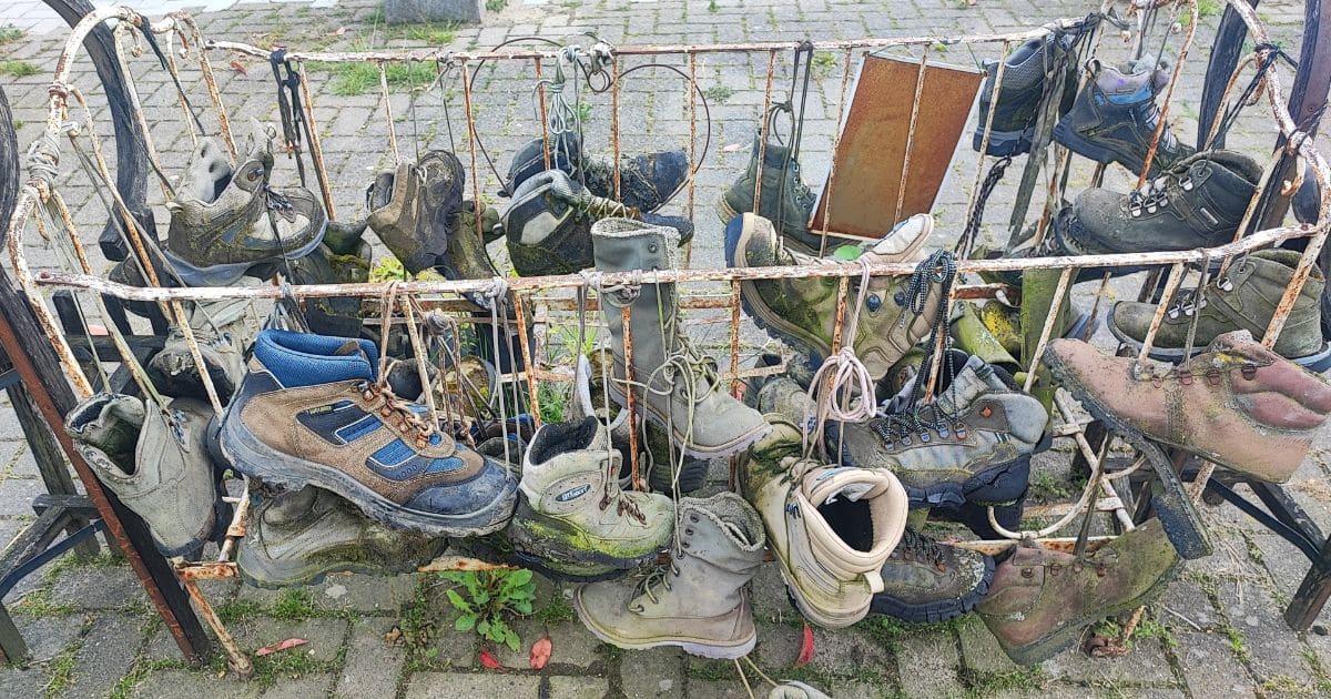 The Ultimate Outdoor Footwear Guide (All Types Explained & More) A bunch of worn out hiking boots hanging on a rack