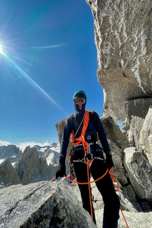 Mountaineering Beginners Guide: Preparing Your First Ascent A climber on a mountain, equipped with a harness and rope, prepares for ascent.
