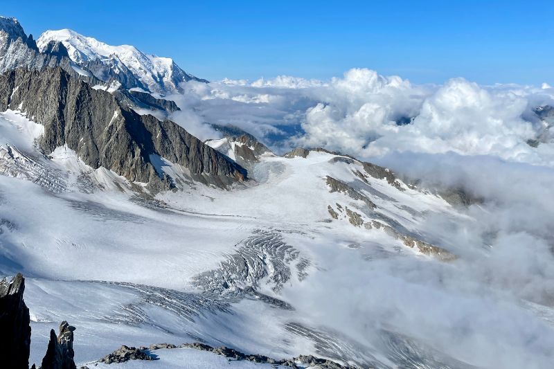Mountaineering Beginners Guide: Preparing Your First Ascent A panoramic view of majestic mountains from a mountain top, showcasing peaks and valleys under a clear blue sky.