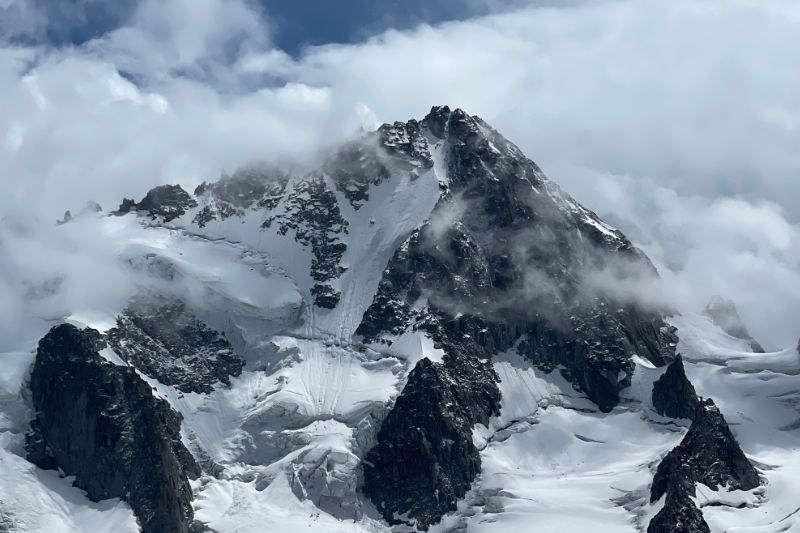 Alpinism vs. Mountaineering: Key Differences Explained alpinist with crampons walking up an icy slope carrying rope and gear