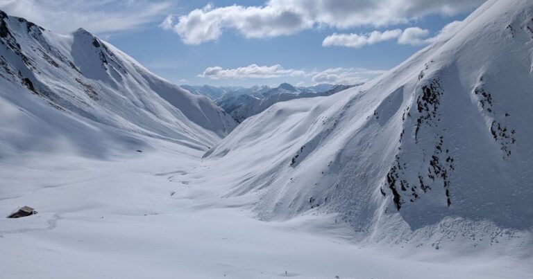 Avalanche Safety Guide: Prepare, Survive & Rescue Small home between two snowy hills that is almost completely covered in snow by an avalanche