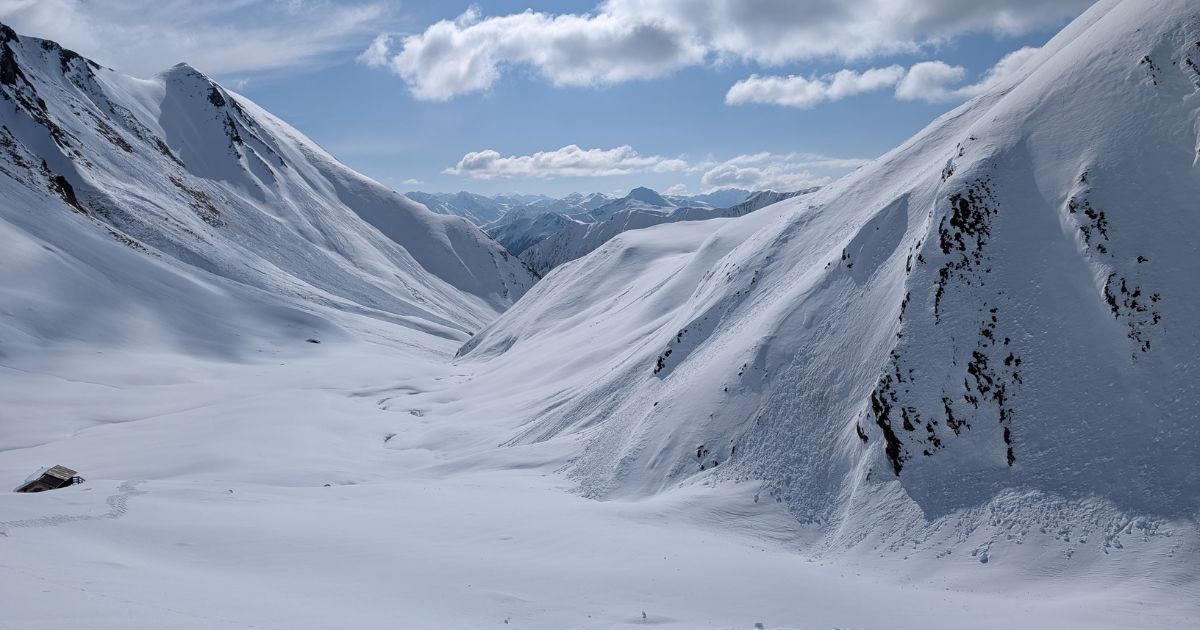 Avalanche Safety Guide: Prepare, Survive & Rescue Small home between two snowy hills that is almost completely covered in snow by an avalanche