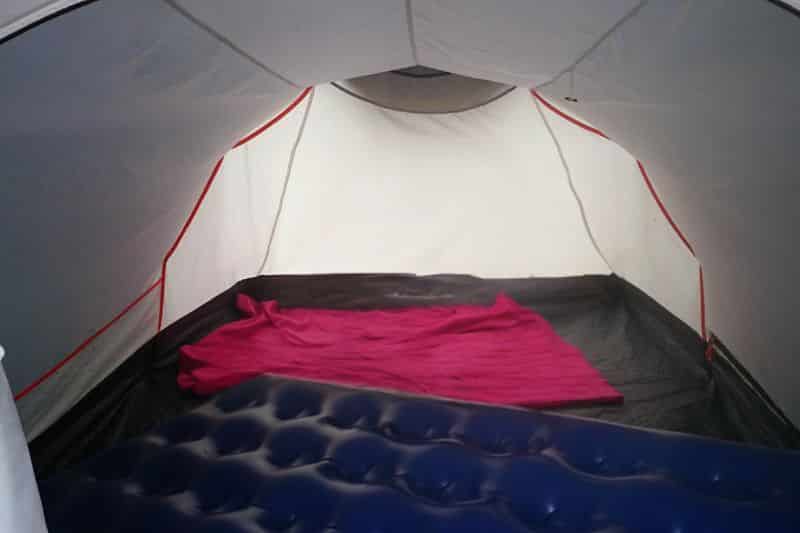 Camping For Beginners: 8 Tips For First Time Camping Trips Inside of a large tent. A airbed is on the floor along with a pink blanket
