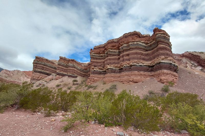How to Turn Wild Camping Into a Glamping Experience A striking red rock formation rises against a clear blue sky in a vast desert landscape.