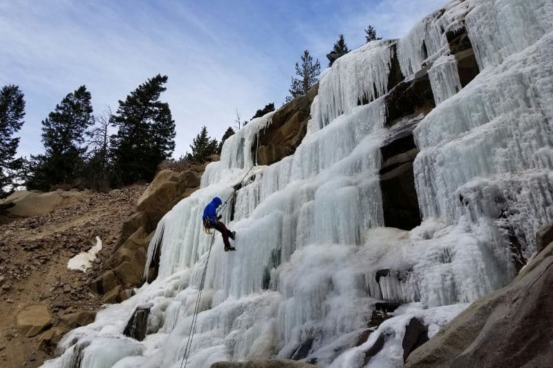 Essential Rope Skills & Knots for Mountaineering Mountaineer rappelling from a frozen waterfall