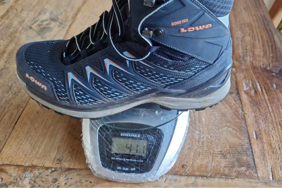 Lowa Innox Pro GTX Mid Review (2026 Test Results) A Lowa Innox Pro hiking boot on a scale. The displays states it's 411 grams