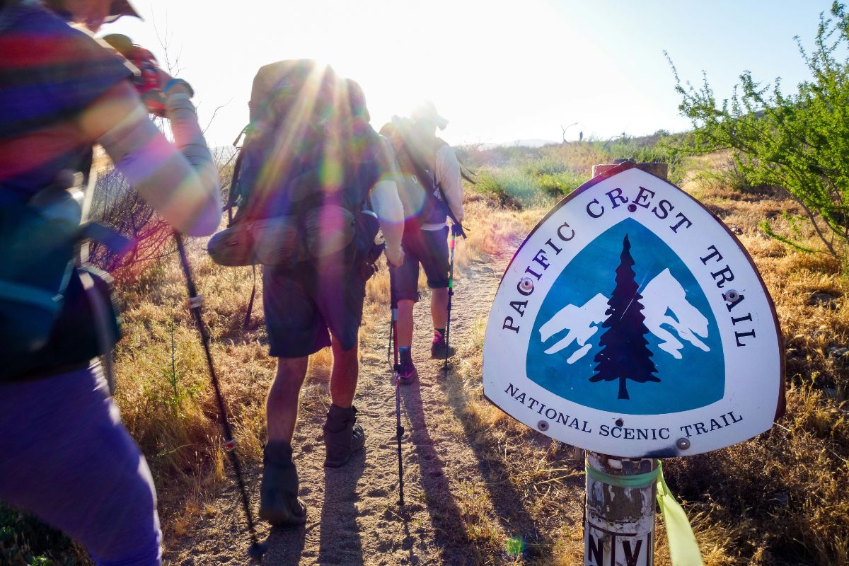 Pacific Crest Trail Guide (Thru-Hike Planning Tips) Hikers passing a PCT Sign on a sunny day
