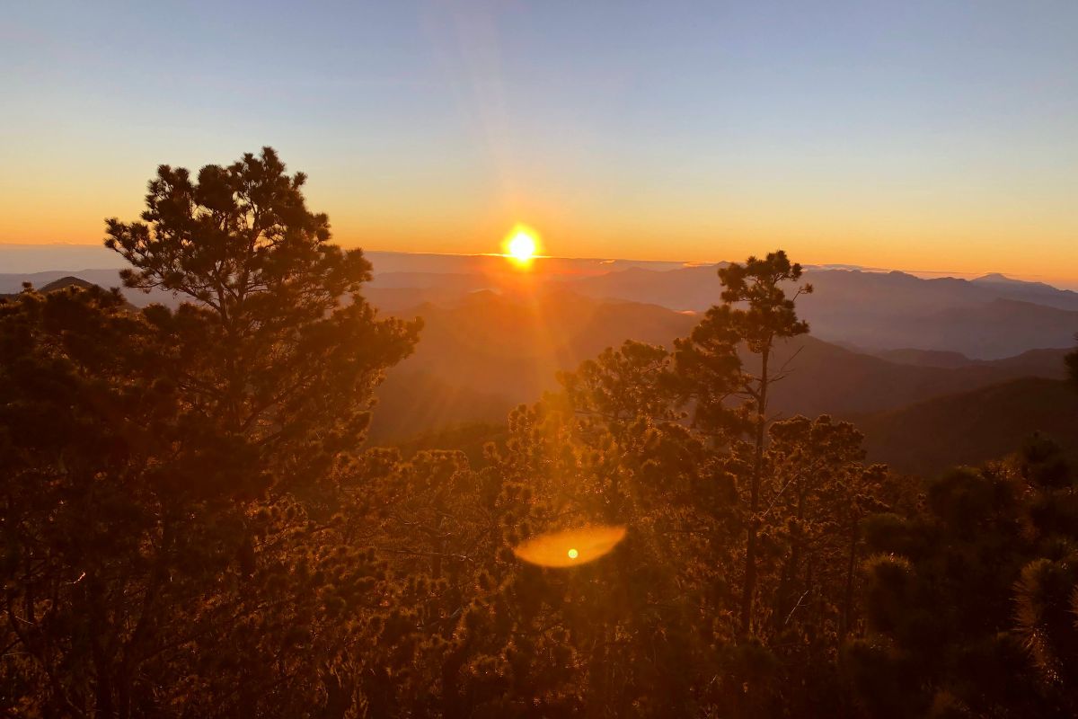 Pacific Crest Trail Guide (Thru-Hike Planning Tips) the sun is rising over the mountainous landscape of the PCT