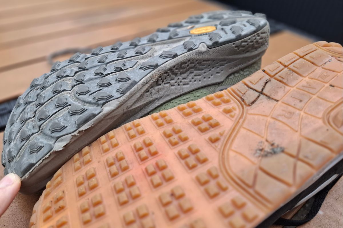 Hiking Terms: The Complete Trail & Gear Glossary. Two outsoles side by side: a trail shoe with deep, widely spaced chevron lugs next to the shallow, dense square tread of a road shoe