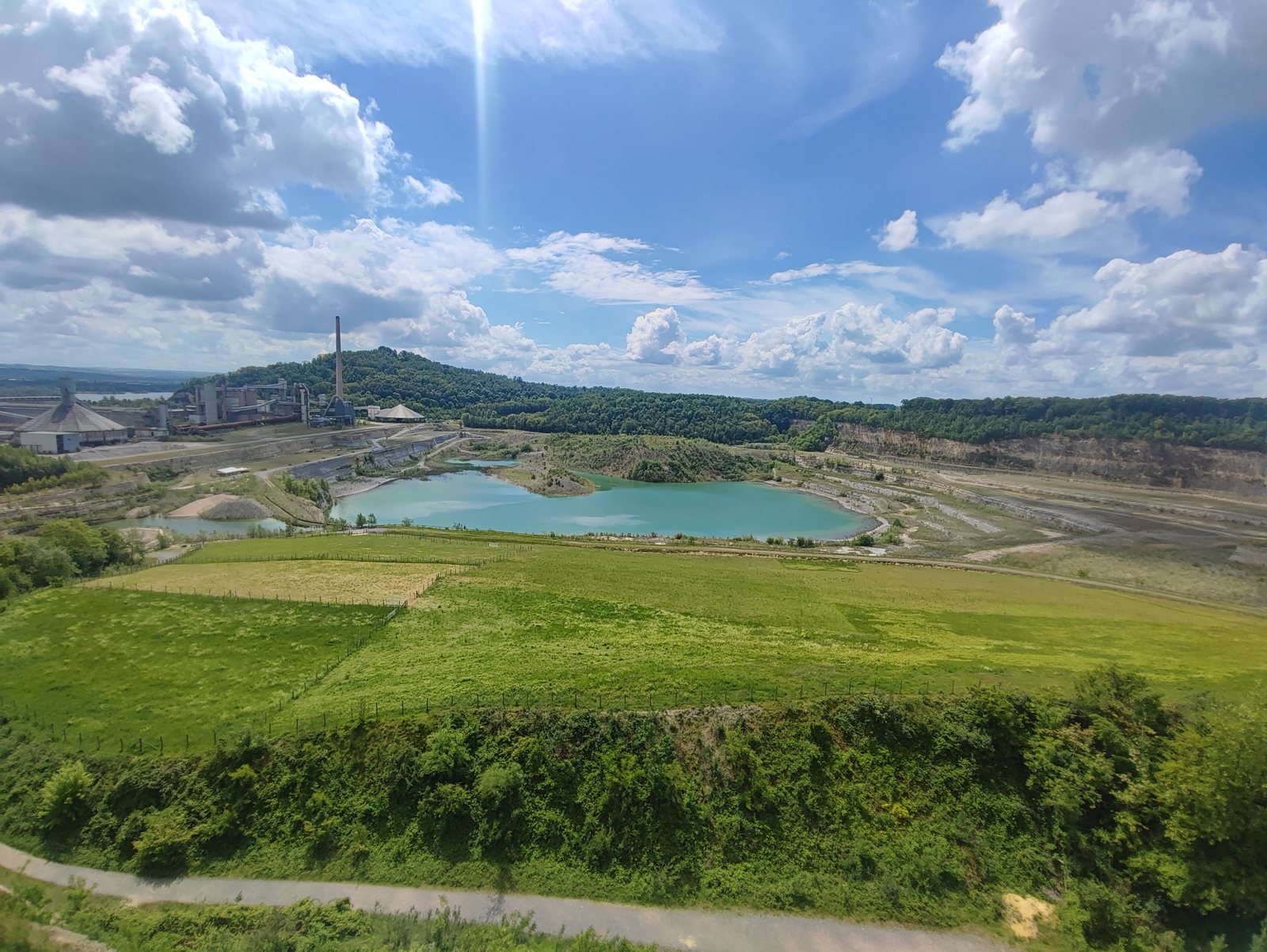 I Walked Four Days of the Pieterpad Without Booking a Single Bed View from the Sint-Pietersberg over a former marl quarry with a turquoise lake, under a blue sky with cumulus.