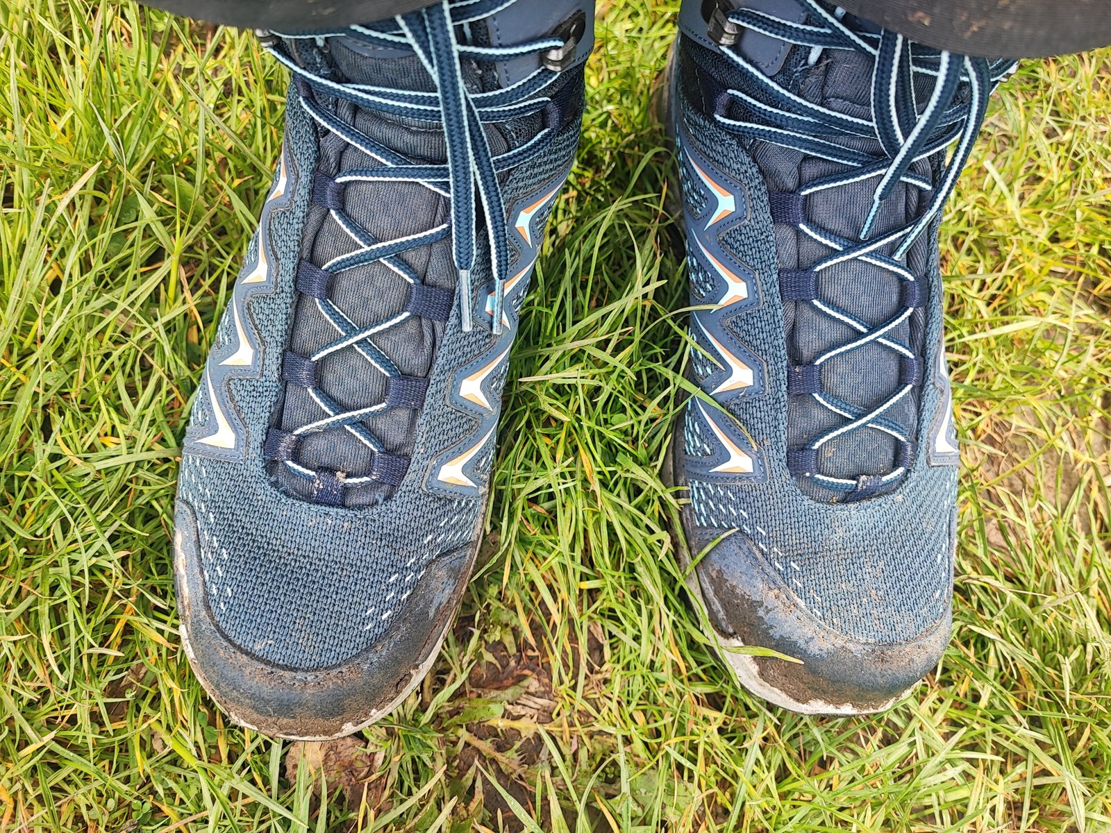 I Walked Four Days of the Pieterpad Without Booking a Single Bed Overhead view of a pair of navy Lowa Innox Pro GTX Mid boots, muddy, standing in wet grass.