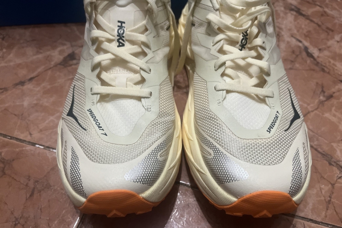 Front view of a pair of women's HOKA Speedgoat 7 Wide trail running shoes in cream and orange