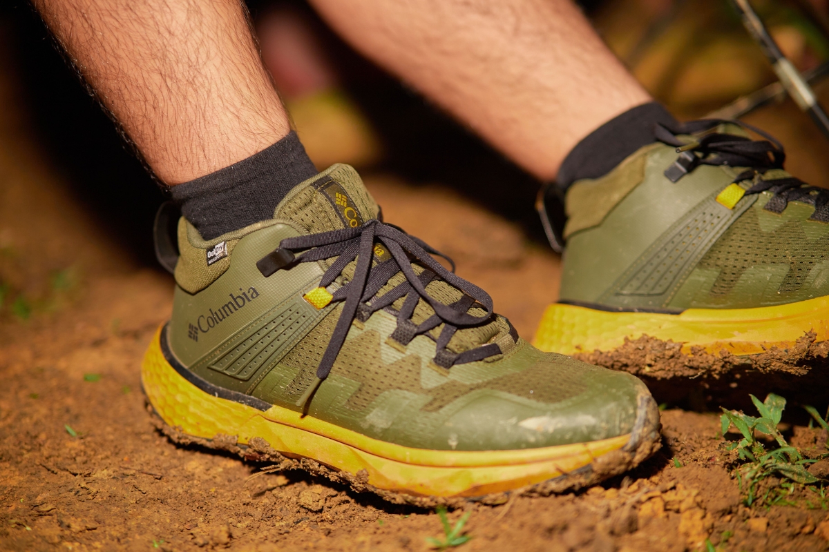 Green Columbia hiking shoes worn on a muddy trail
