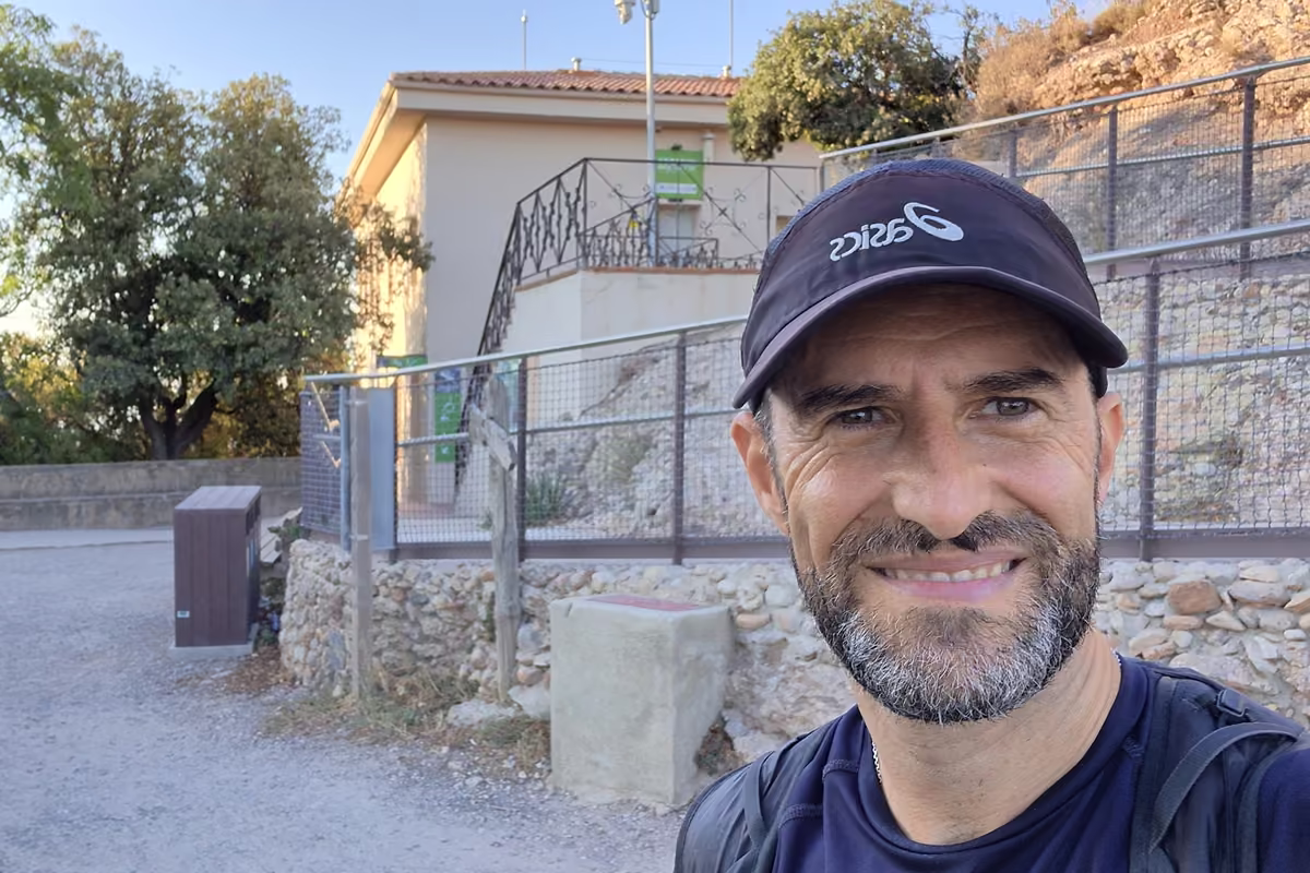 Sergio López Prieto, smiling in a dark cap, taking a selfie beside the upper station of the Sant Joan funicular at the Pla de les Taràntules.