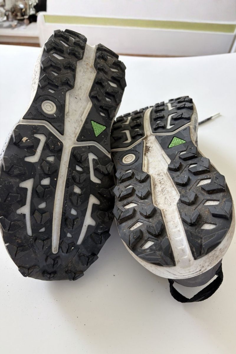TrailTack Green outsoles of the Brooks Caldera 8 with trail dirt between the lugs