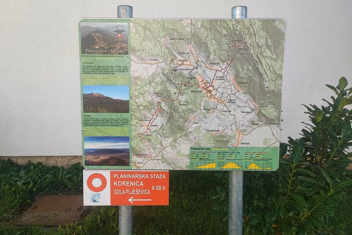 Hiking map board of Plješevica and Mrsinj in Korenica, with a red and white trail sign below reading Korenica to Gola Plješevica, 4:00 h.